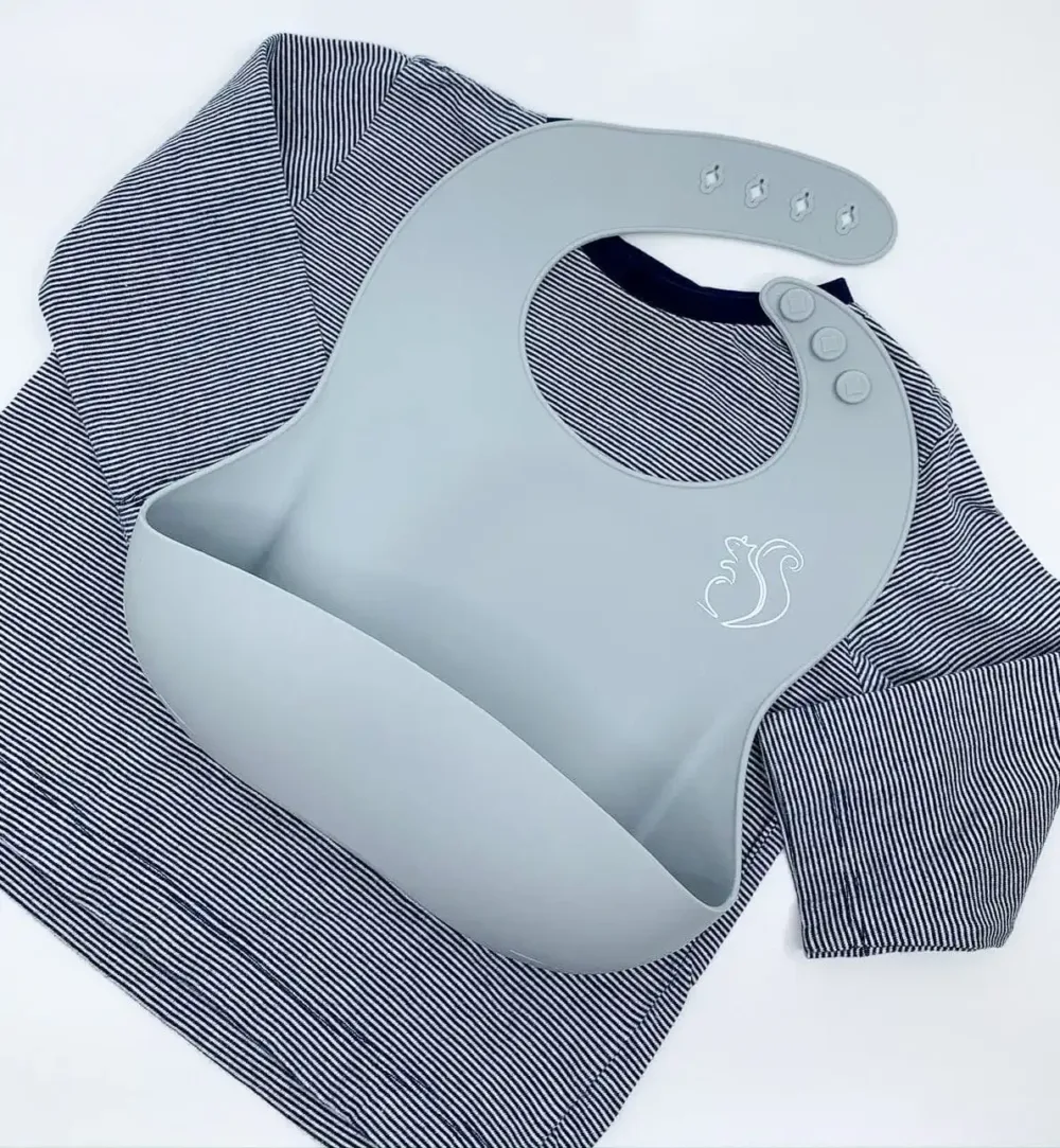 Light blue Silicone Bib with a catcher for a baby on top of a blue striped long-sleeved t-shirt.