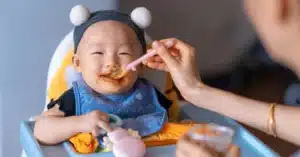 Asian baby being spoon fed puree