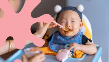 Asian Baby Being fed puree in a highchair.